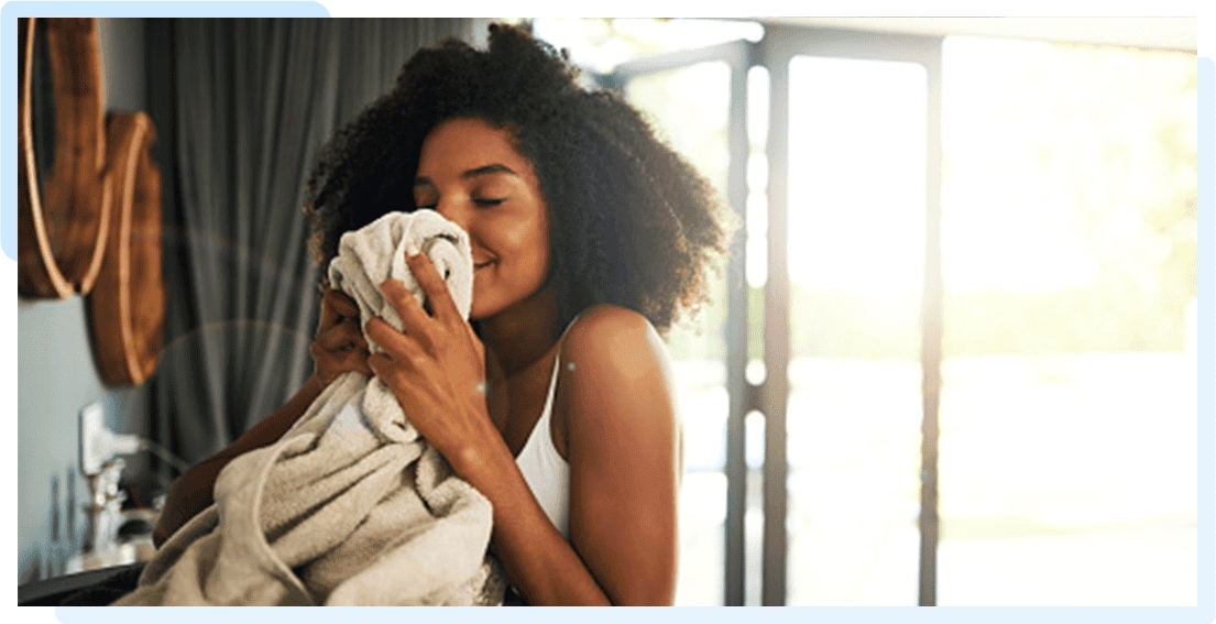 A woman enjoying the delightful fragrance of her laundry washed with Sta-soft  